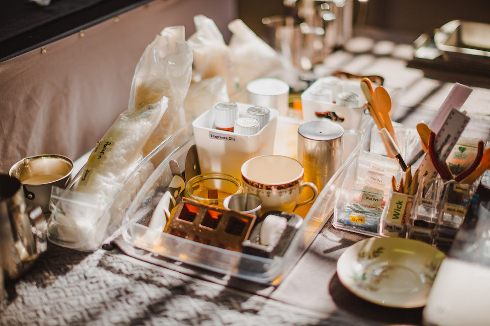 A selection of candle making equipment and materials displayed on a table